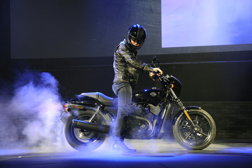 Photo of a man riding a motorcycle on stage. Motorcycle is burning out