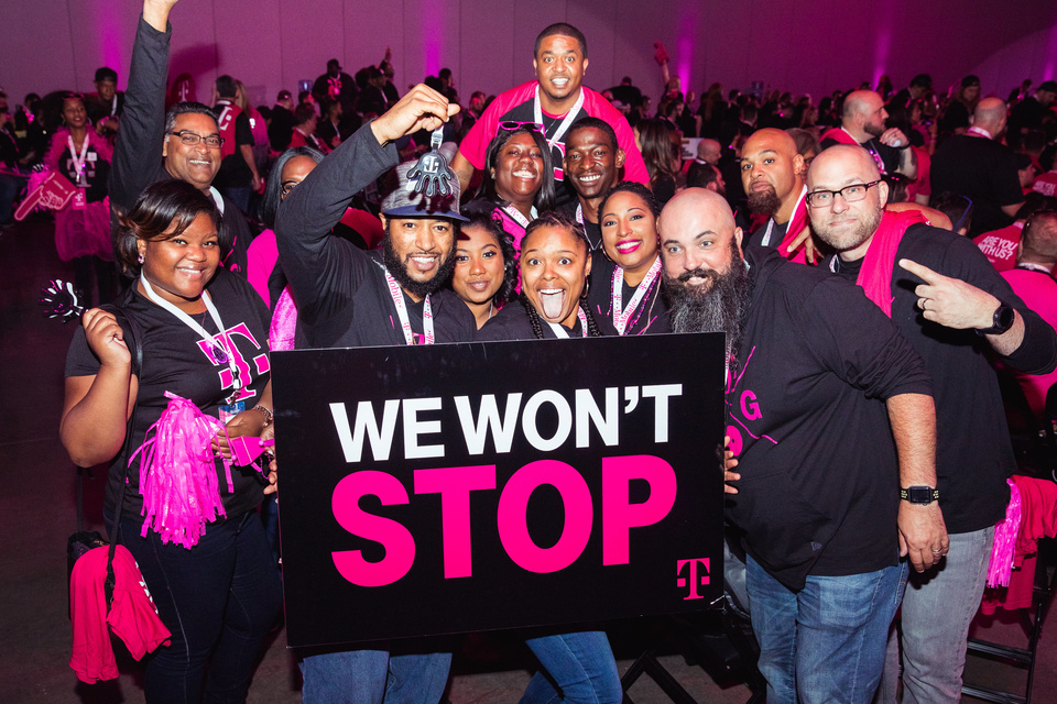 Photo of a Crowd of event attendees with a T-Mobile branded sign that reads "We Won't Stop"