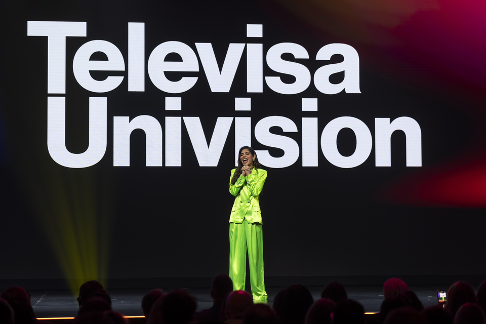 Photo of a woman speaking to an audience on a stage with a Televisa Univision backdrop