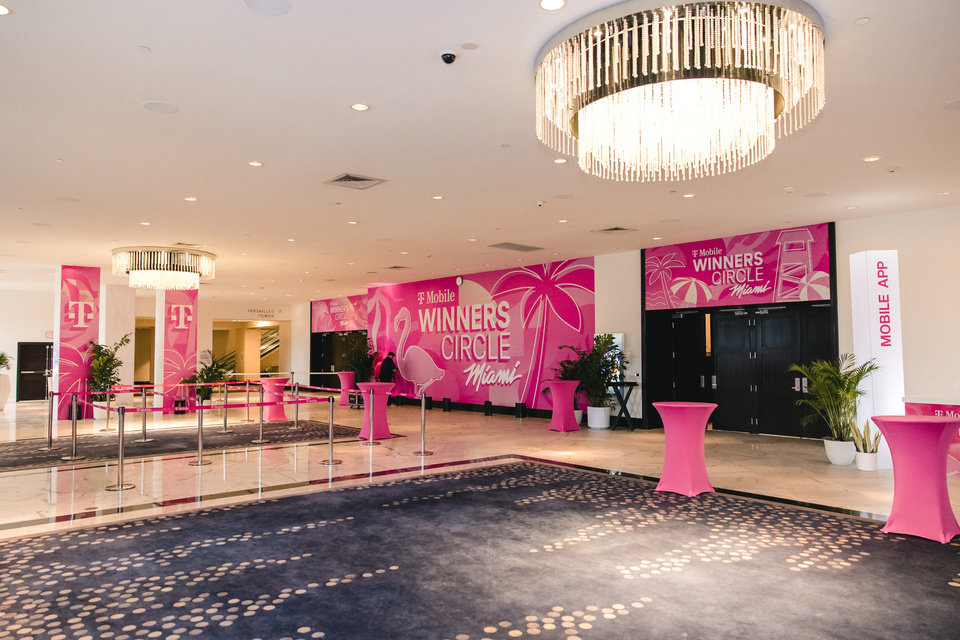 Photo of T-Mobile Winner Circle Miami Reception Area with magenta tables and tropical signage
