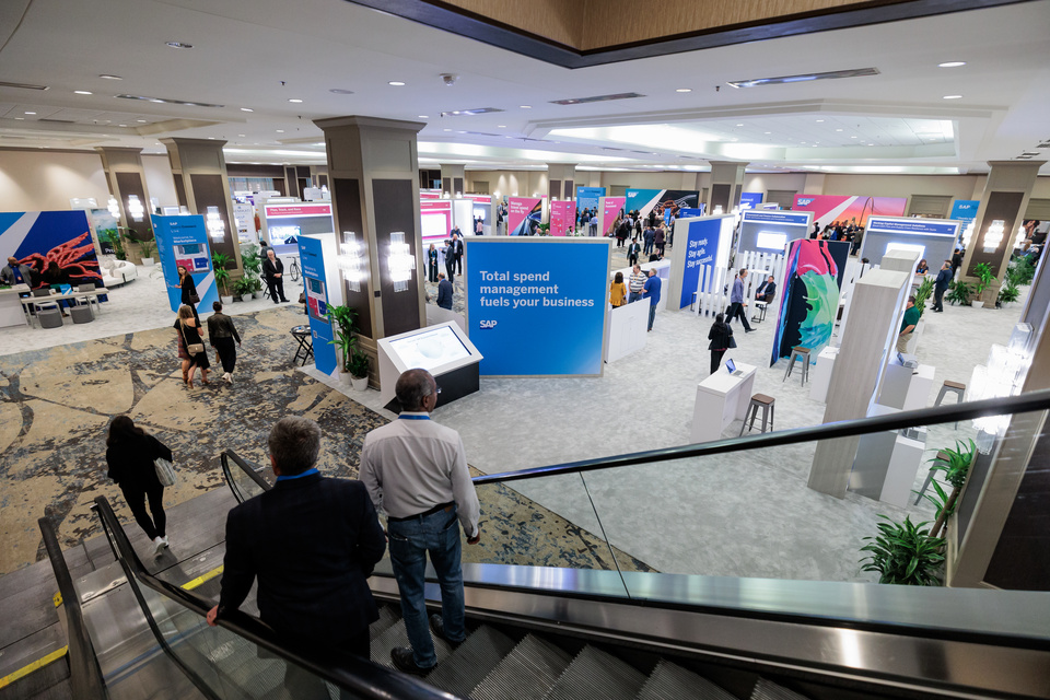 Image of 2 people going down an escalator into an expo with SAP Connect branding